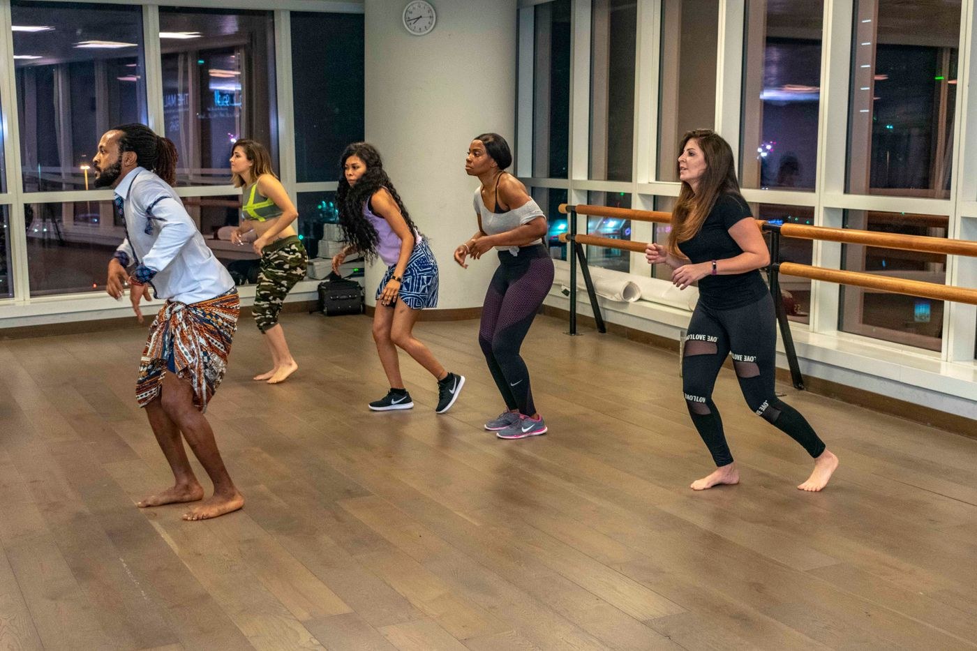 Adults following an instructor in a group dance-based fitness class.