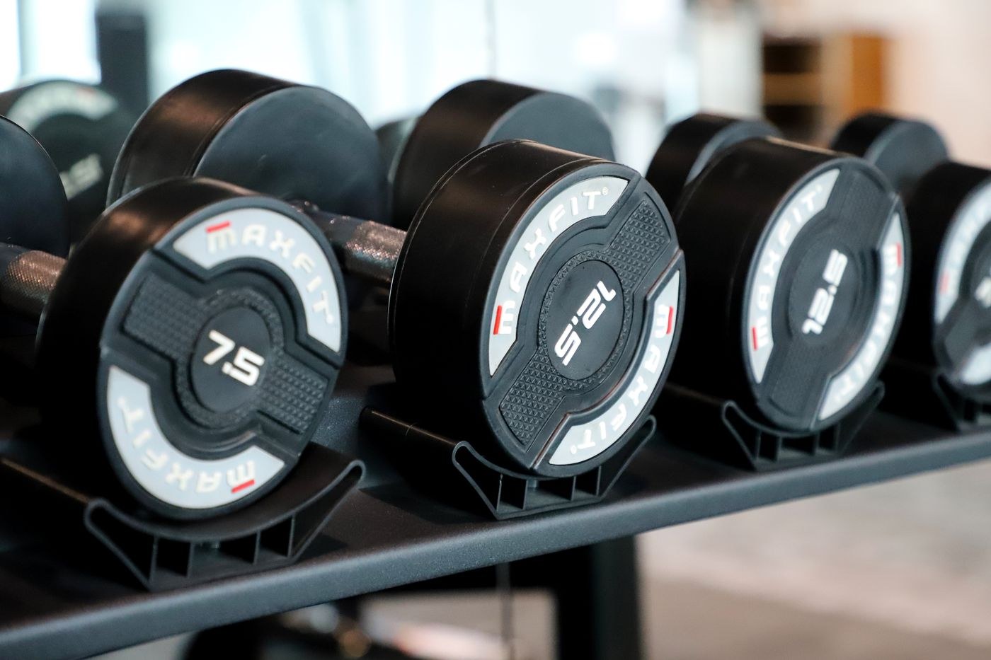 Dumbbells with different marked weights arranged on a gym rack.
