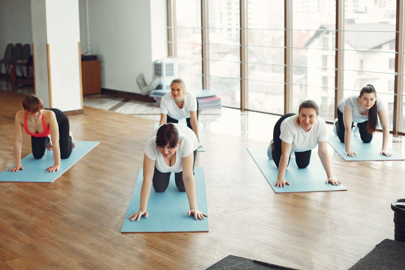 An instructor and participants spaced across mats in a studio.