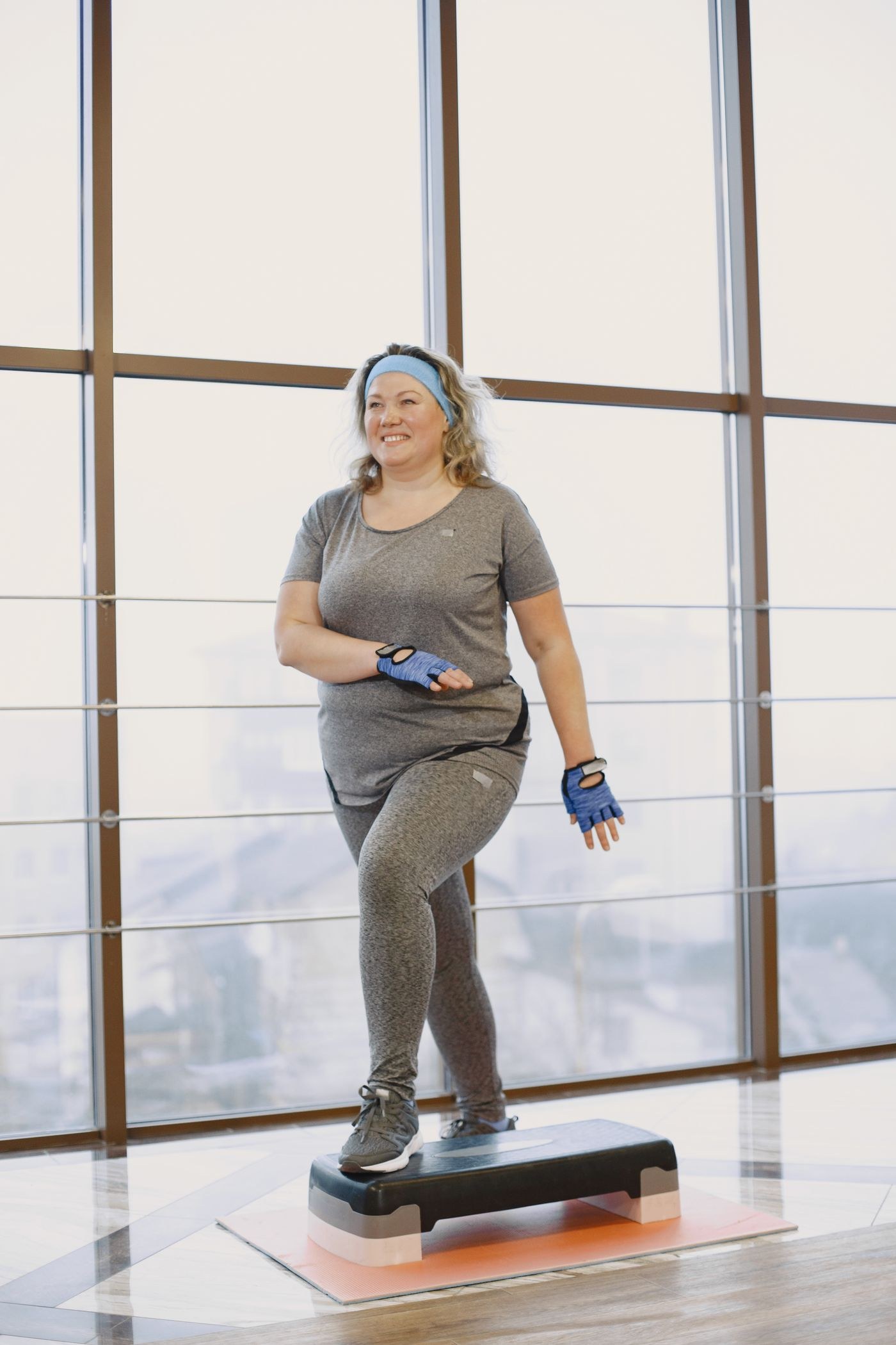 A woman stepping onto a low exercise platform.