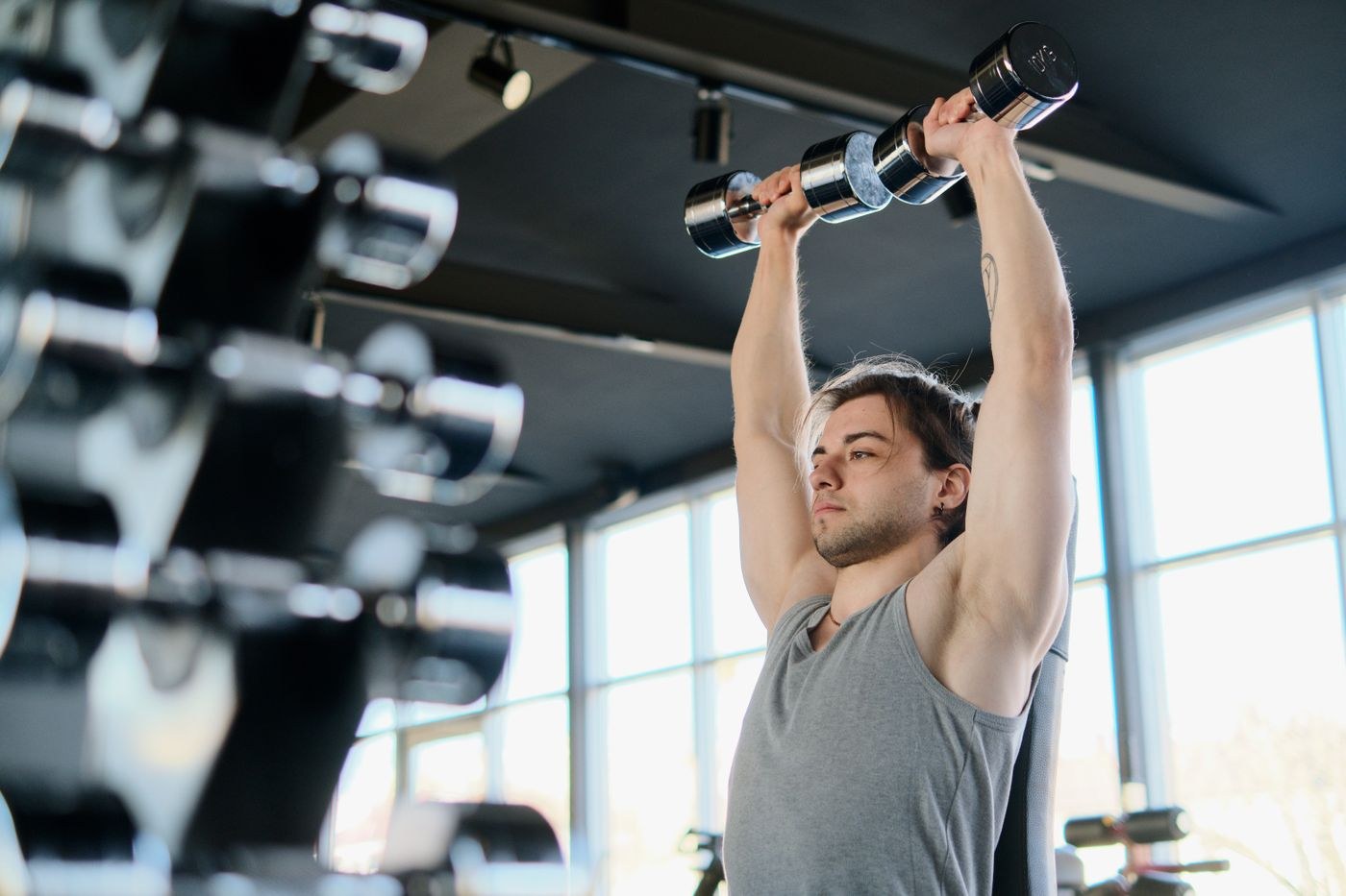 A man holding two dumbbells overhead during a shoulder press.