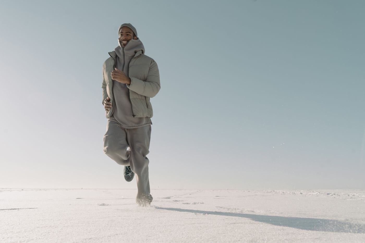 A runner exercising in bright winter daylight on snow.