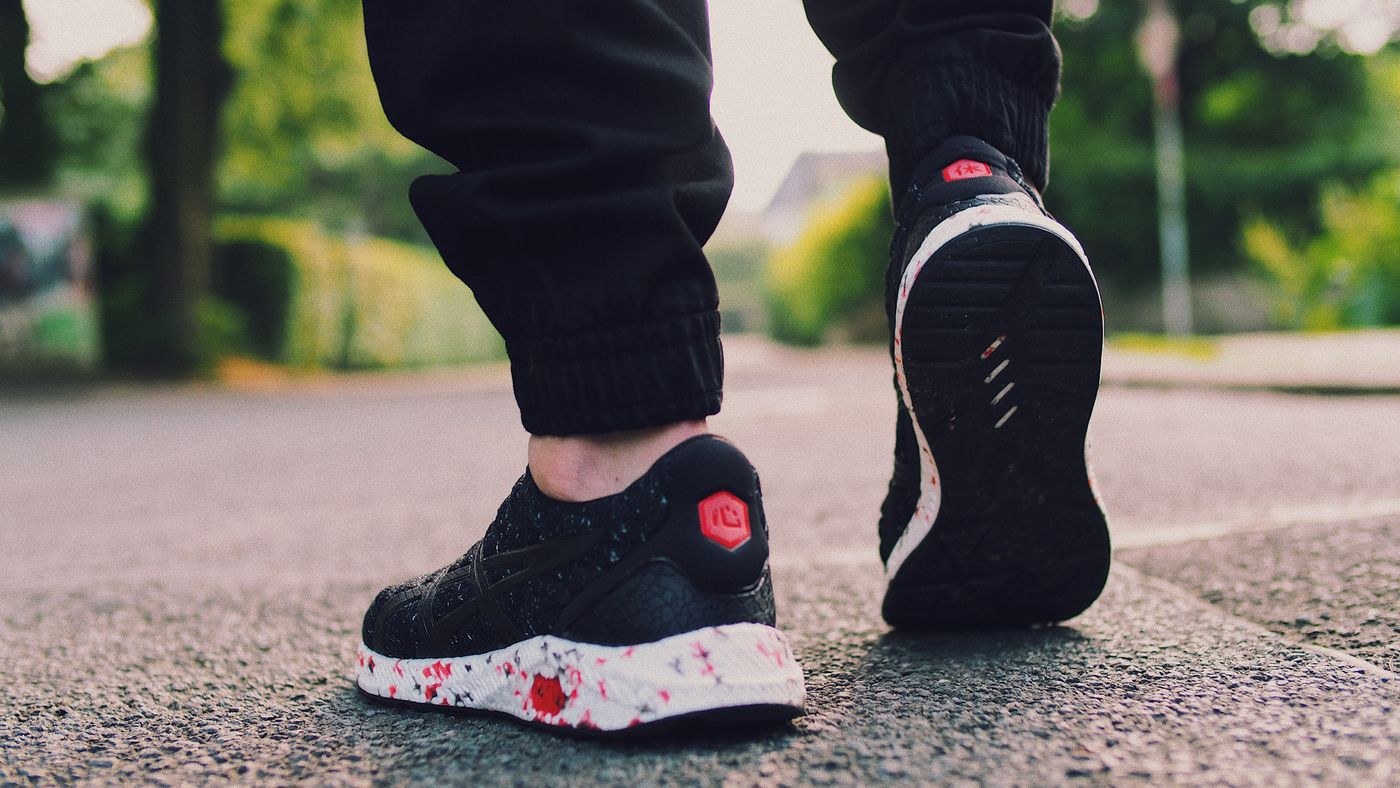 A person walking along a paved path in lace-up sports shoes.