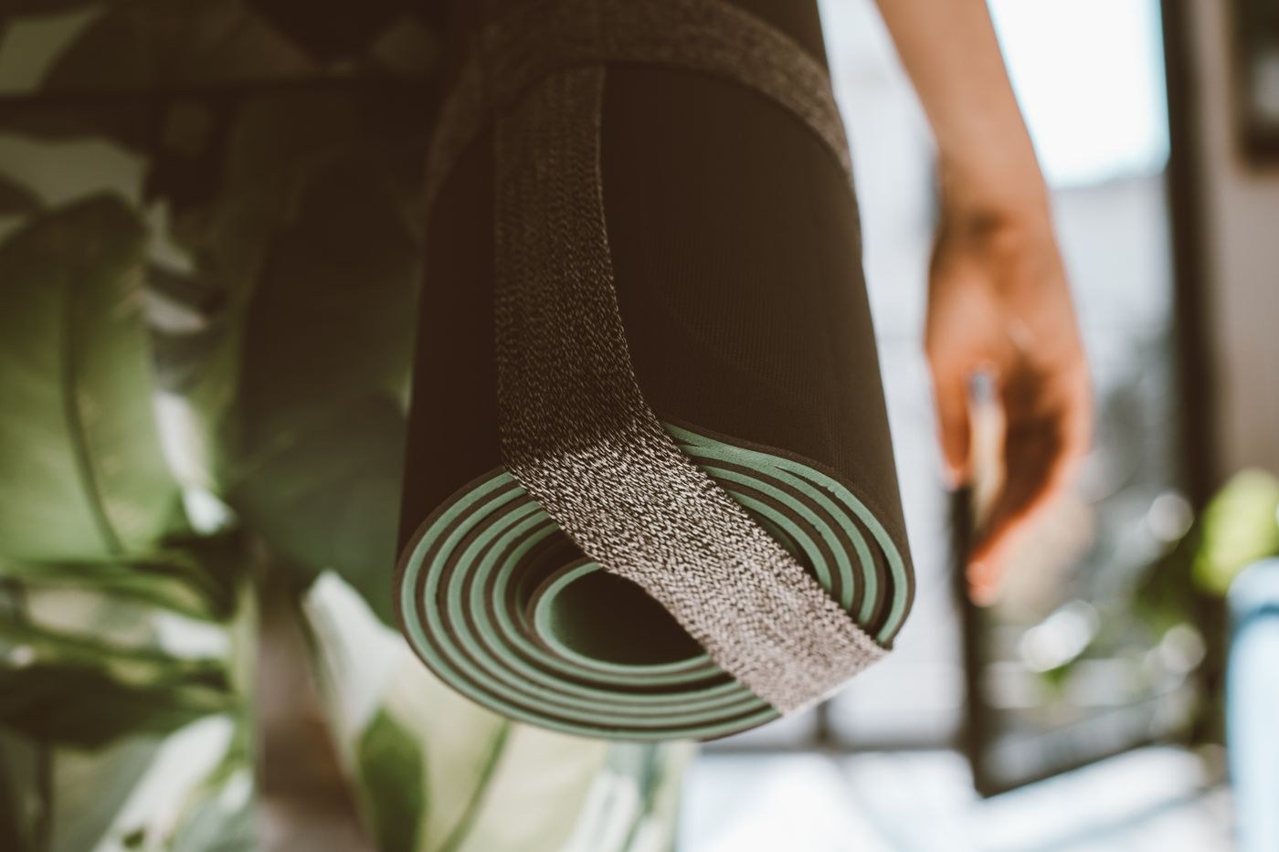 A rolled exercise mat secured with a fabric carrying strap.