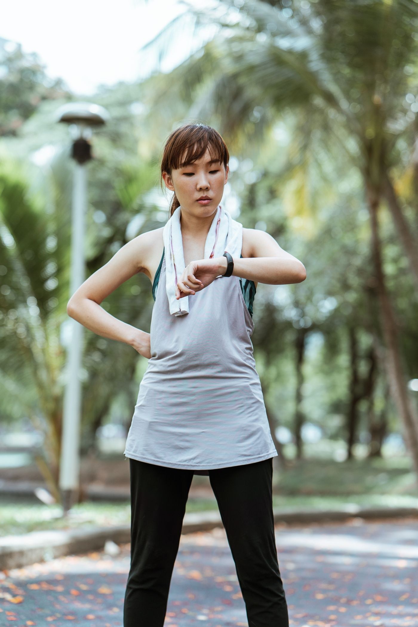 A woman wearing a sleeveless exercise top while checking her watch.