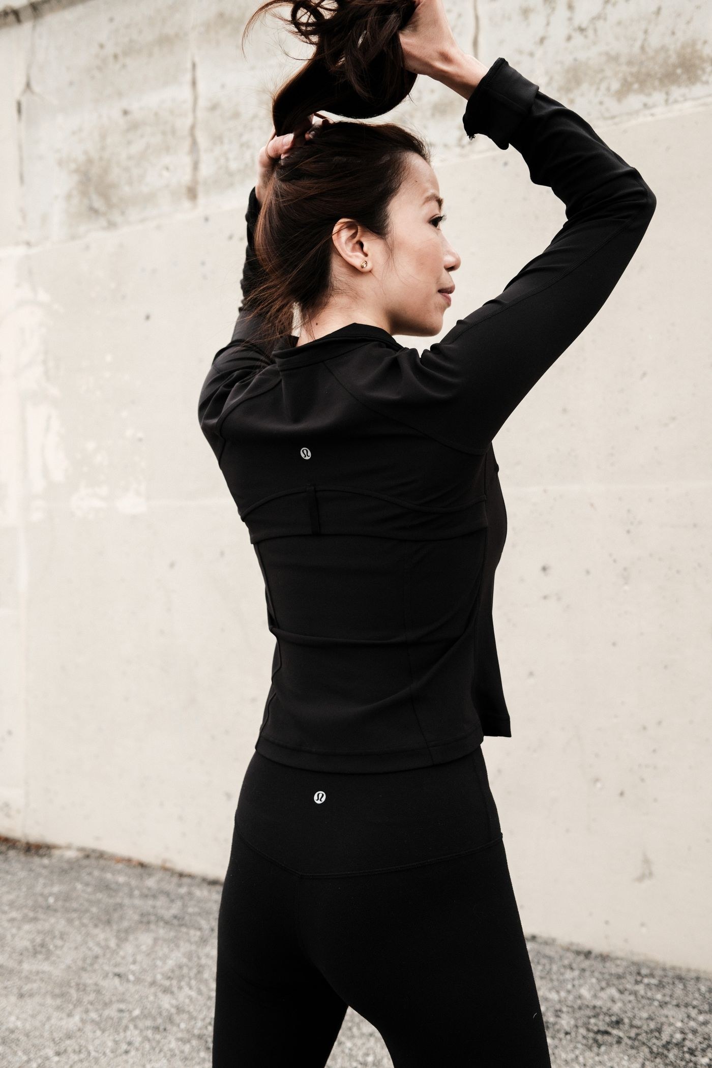 A woman wearing a long-sleeved black training layer outdoors.