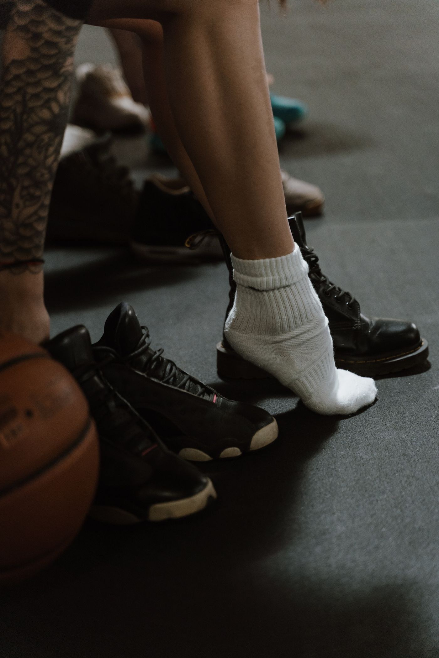 An ankle sock beside a pair of training shoes on a gym floor.