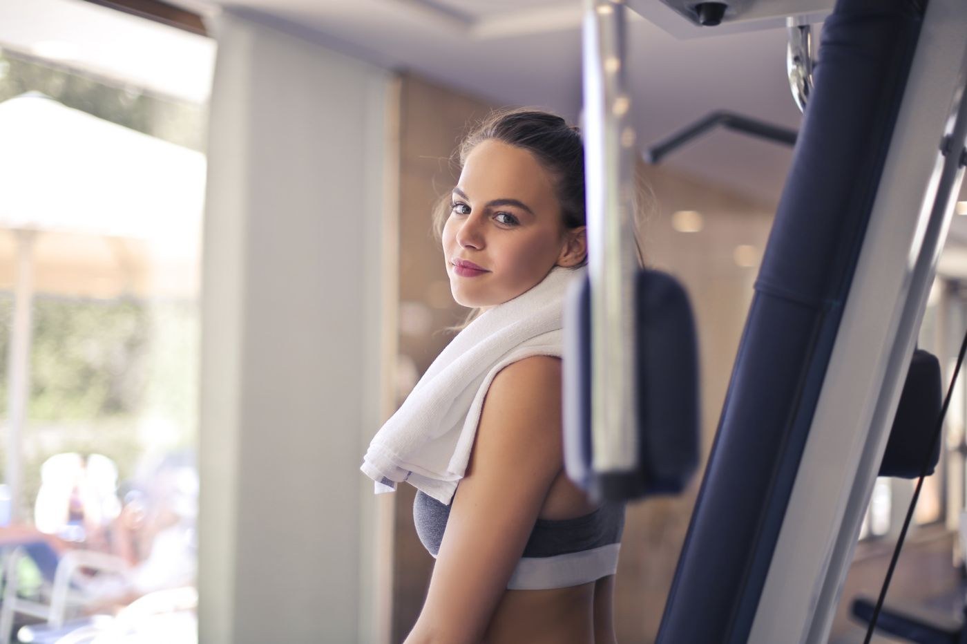 A woman with a small towel over her shoulder in a gym.