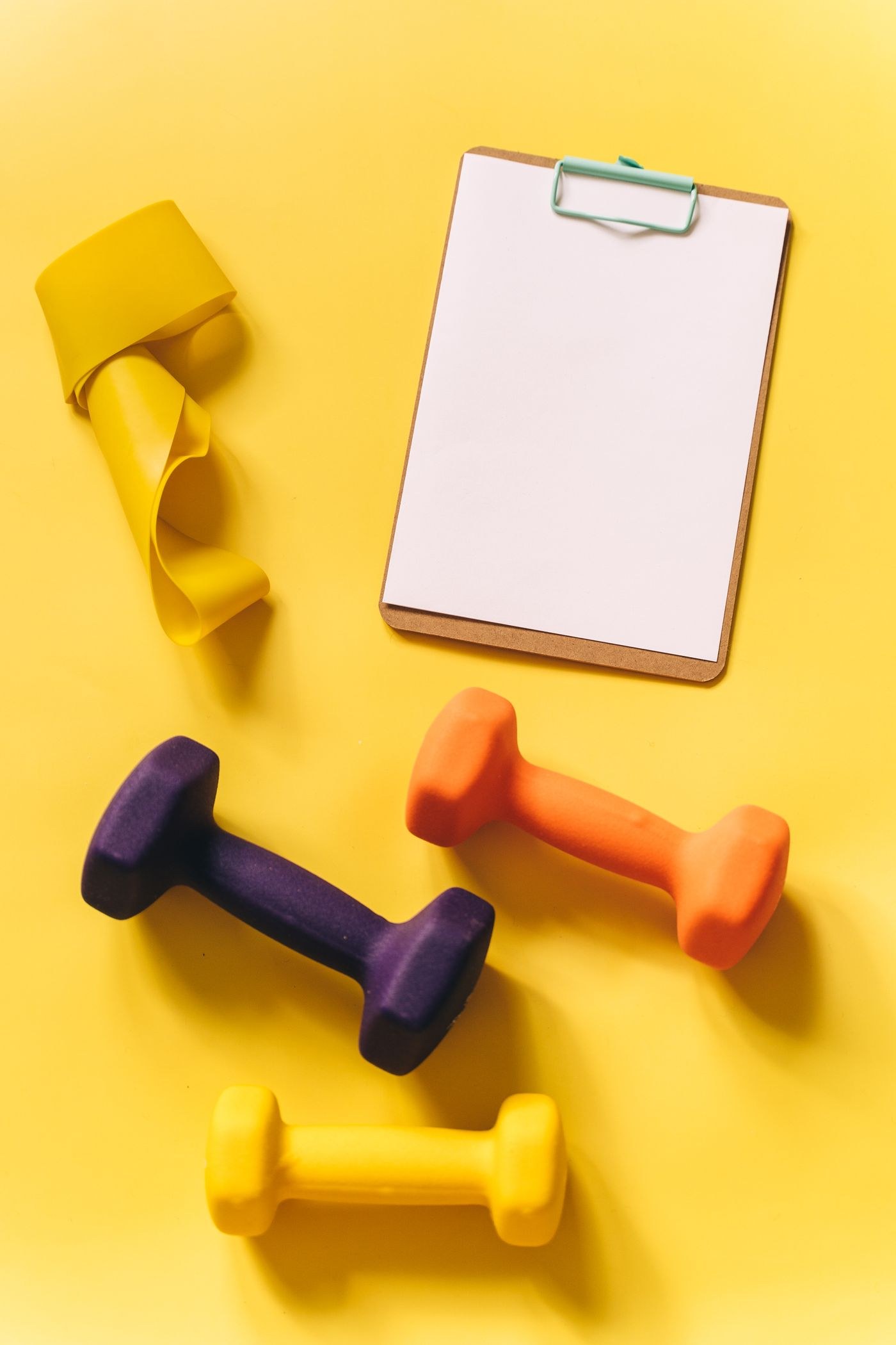 Different-sized dumbbells beside a clipboard for planning changes to a session.