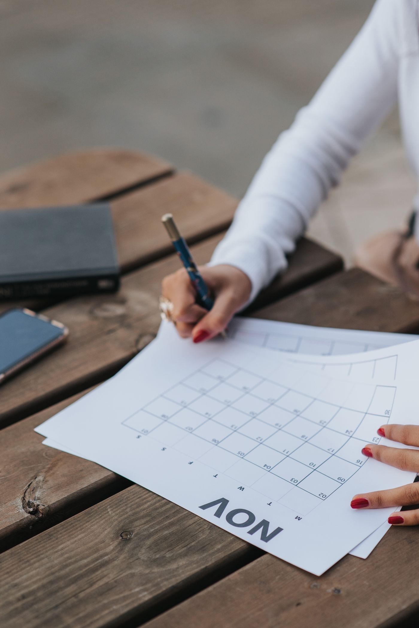 A person reviewing and writing on a monthly paper calendar.