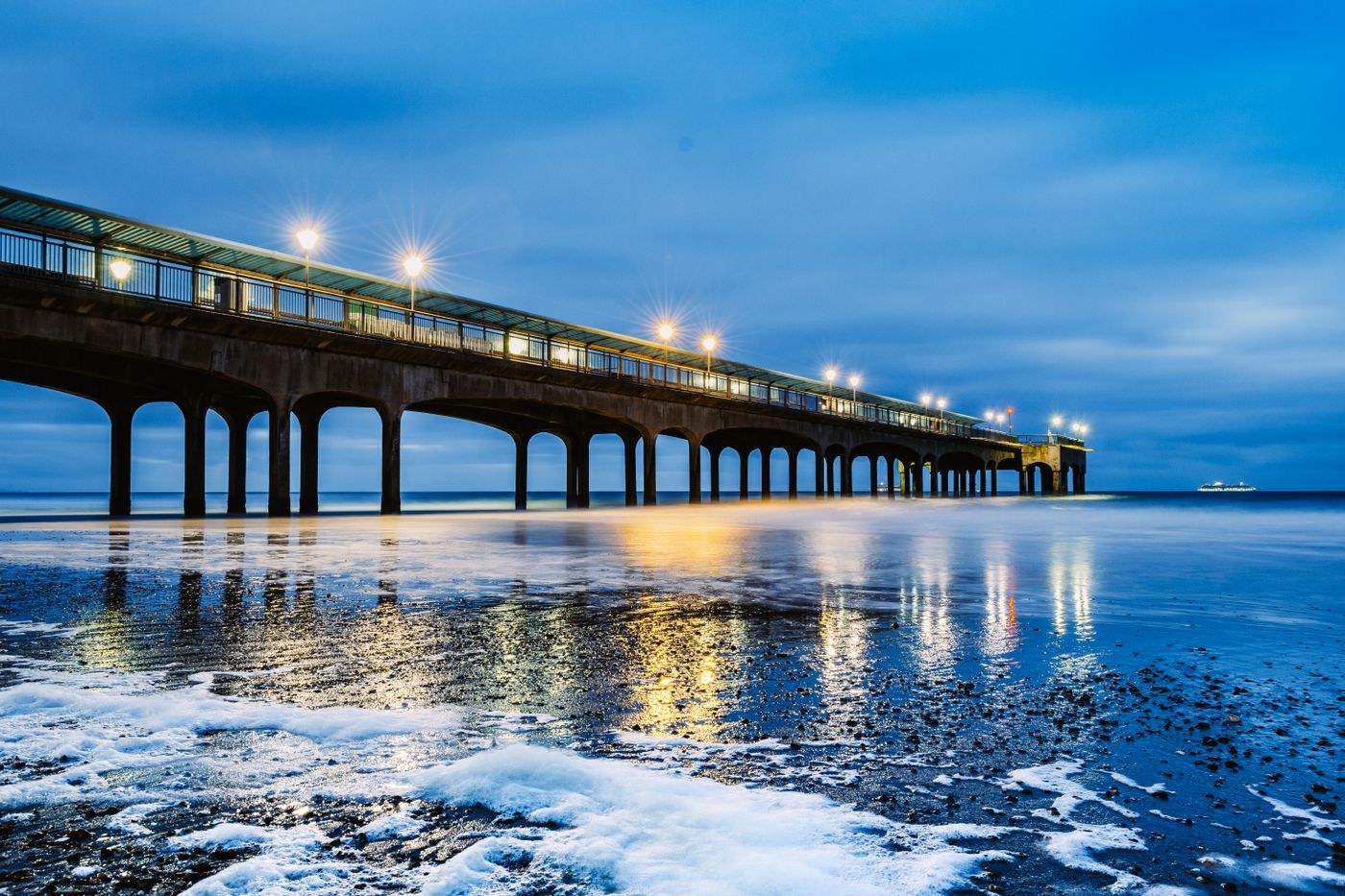 Boscombe Pier reflected in the sea at dusk.